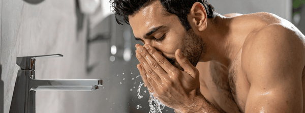 A man washes his face over a skin, splashing water on his oily and acne-prone skin