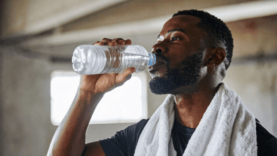 A man drinking from a bottle of water after a sweaty workout