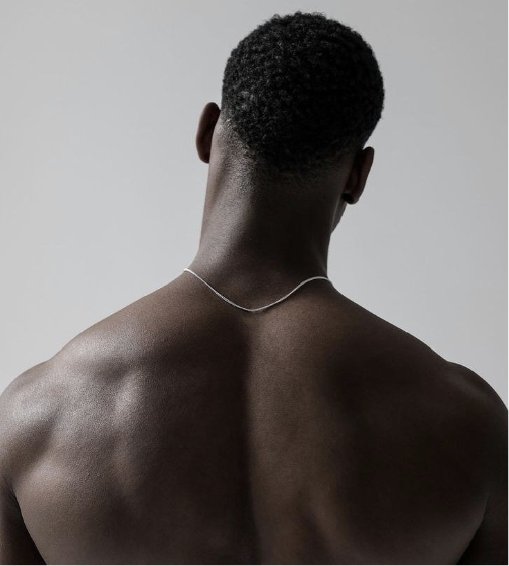Man wearing a silver necklace against a plain background