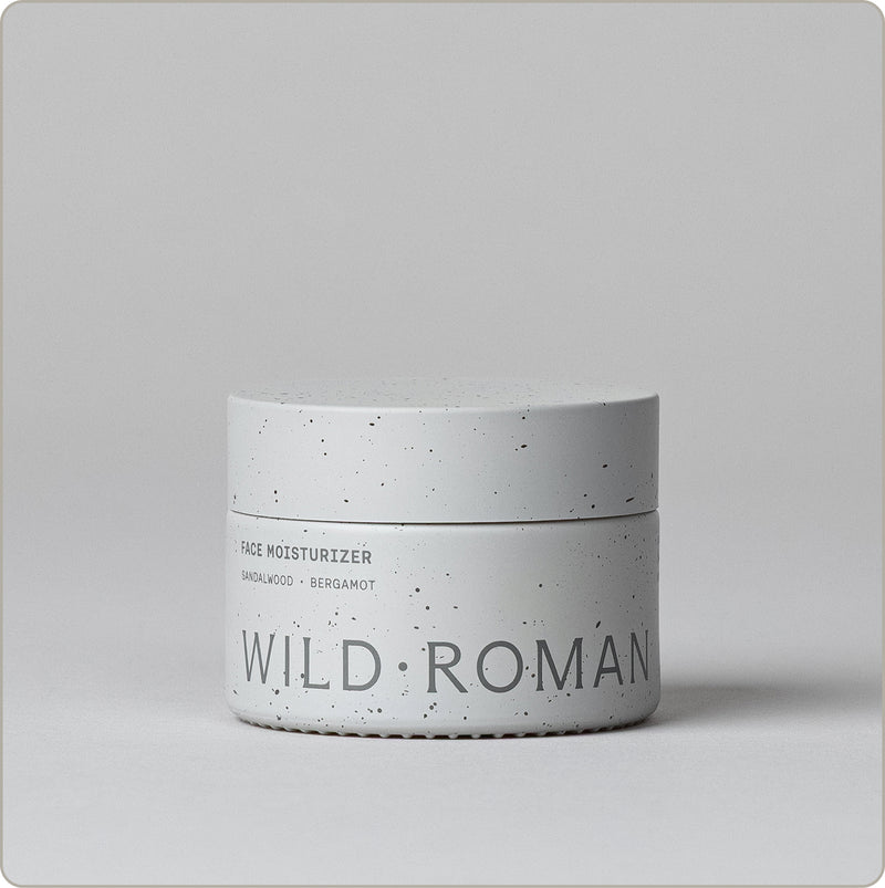 Wild Roman Face Moisturizer in sandalwood and bergamot, speckled white jar on a light gray background