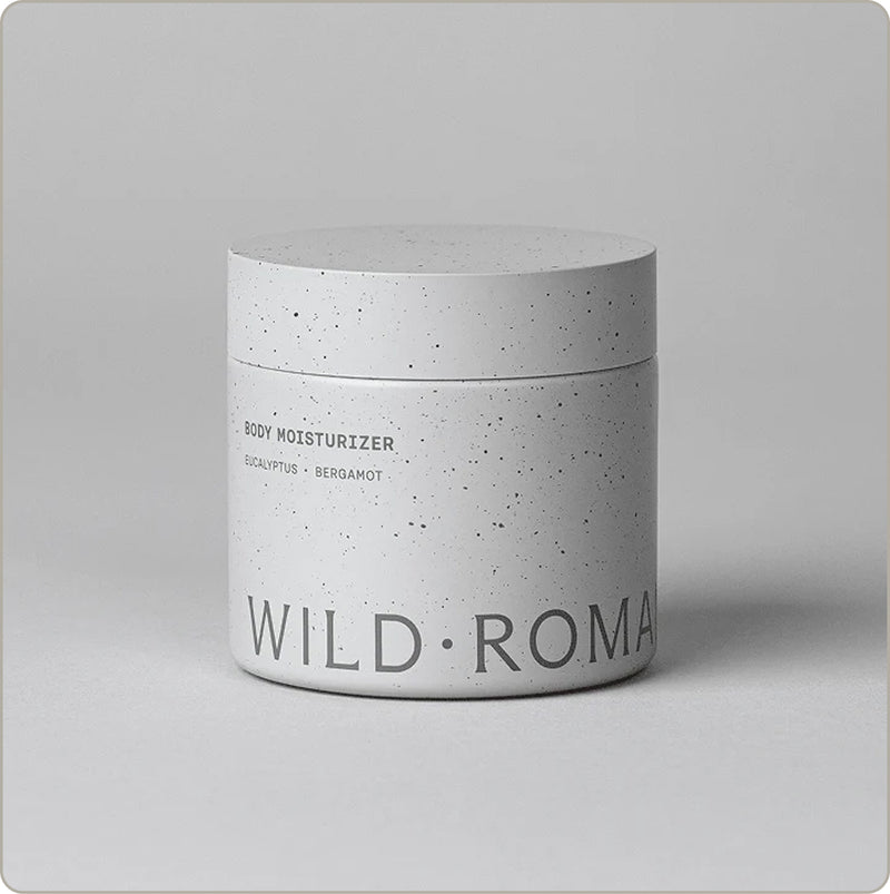 Wild Roman Body Moisturizer in eucalyptus and bergamot, speckled white jar on a light gray background