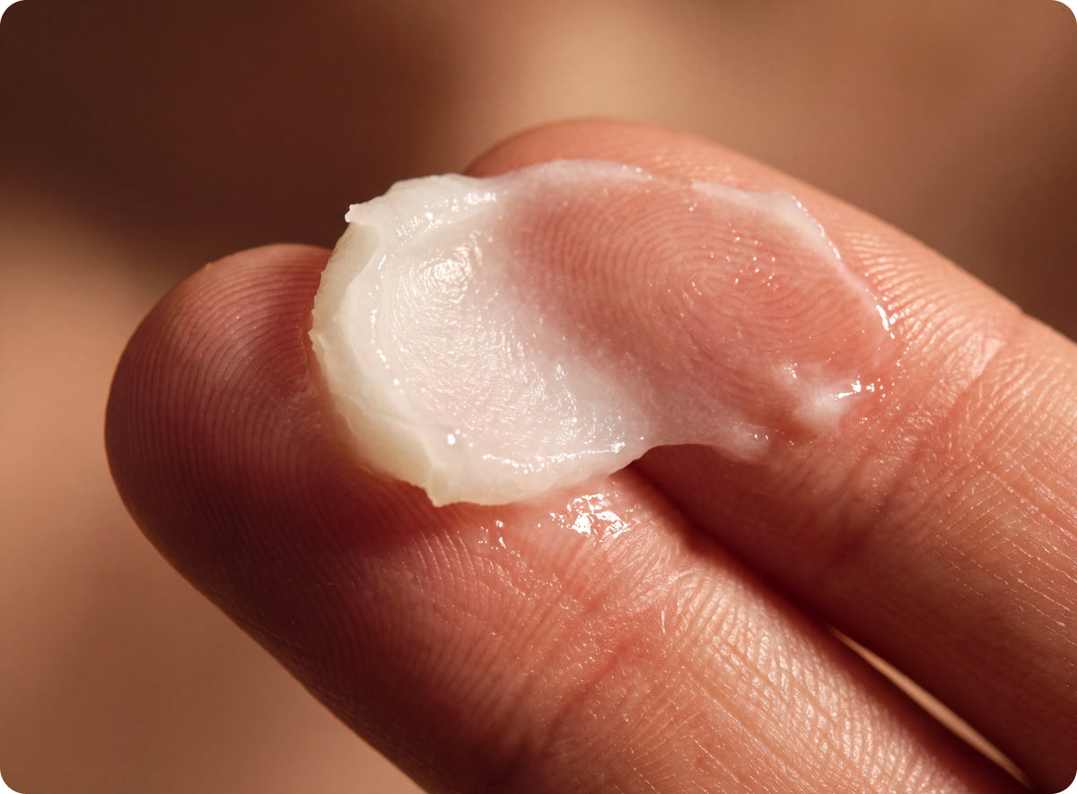 Close-up of a dollop of Wild Roman moisturizer spread across two fingertips