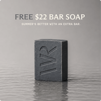 A dark charcoal gray bar of soap with an embossed 'WR' logo, standing on a reflective gray surface. Above it, text reads 'FREE $22 BAR SOAP' and 'SUMMER'S BETTER WITH AN EXTRA BAR.