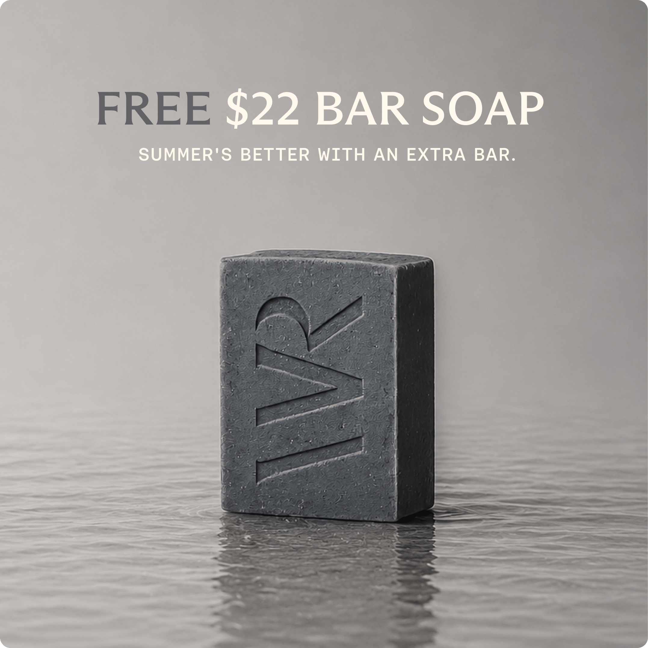 A dark charcoal gray bar of soap with an embossed 'WR' logo, standing on a reflective gray surface. Above it, text reads 'FREE $22 BAR SOAP' and 'SUMMER'S BETTER WITH AN EXTRA BAR.