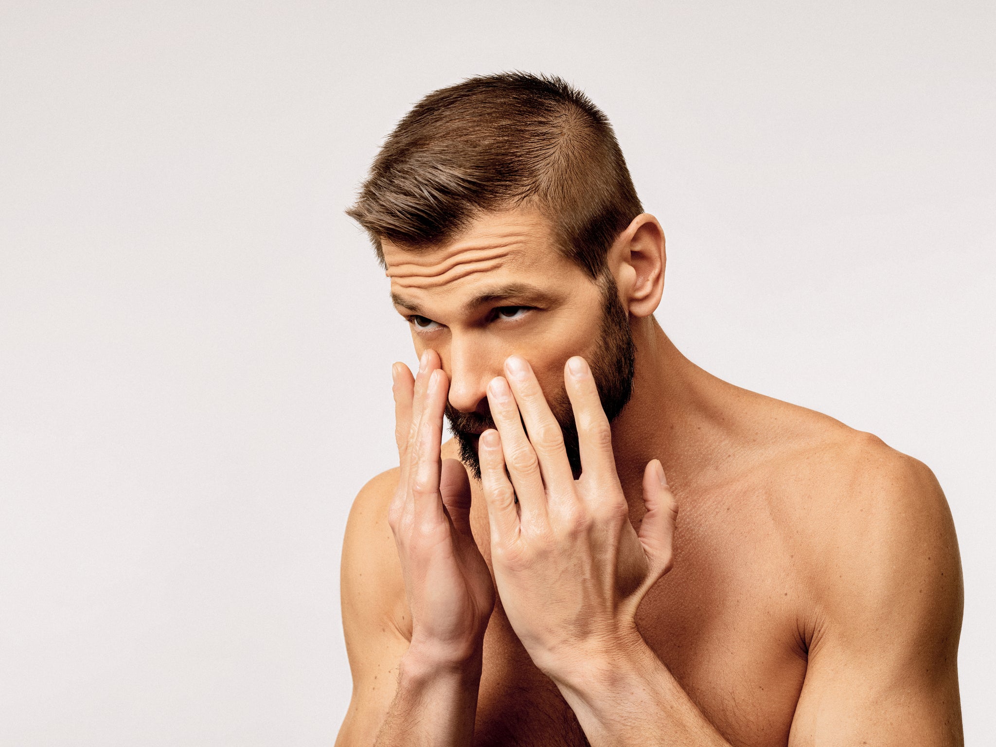 man with a beard applying sea buckthorn berry oil and camellia oil to his face