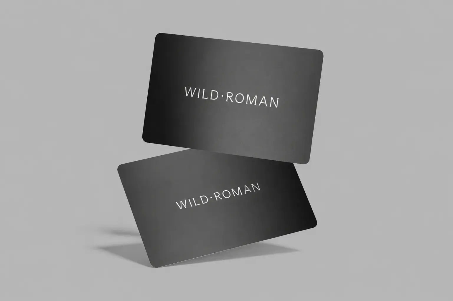 Two black Wild Roman gift cards with 'WILD ROMAN' text on a gray background