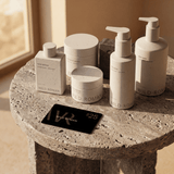 Collection of Wild Roman skincare products on a stone surface with a card displaying the brand name.